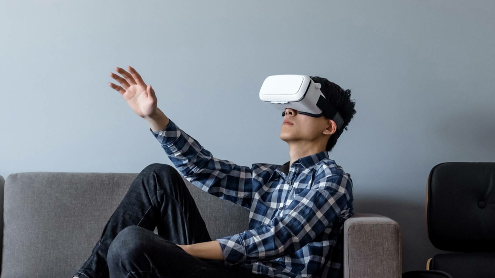 Student im Profil mit VR-Brille auf Sofa