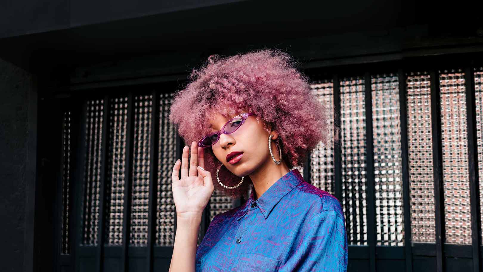 Junge Frau mit Afrofrisur, violetter Brille und 