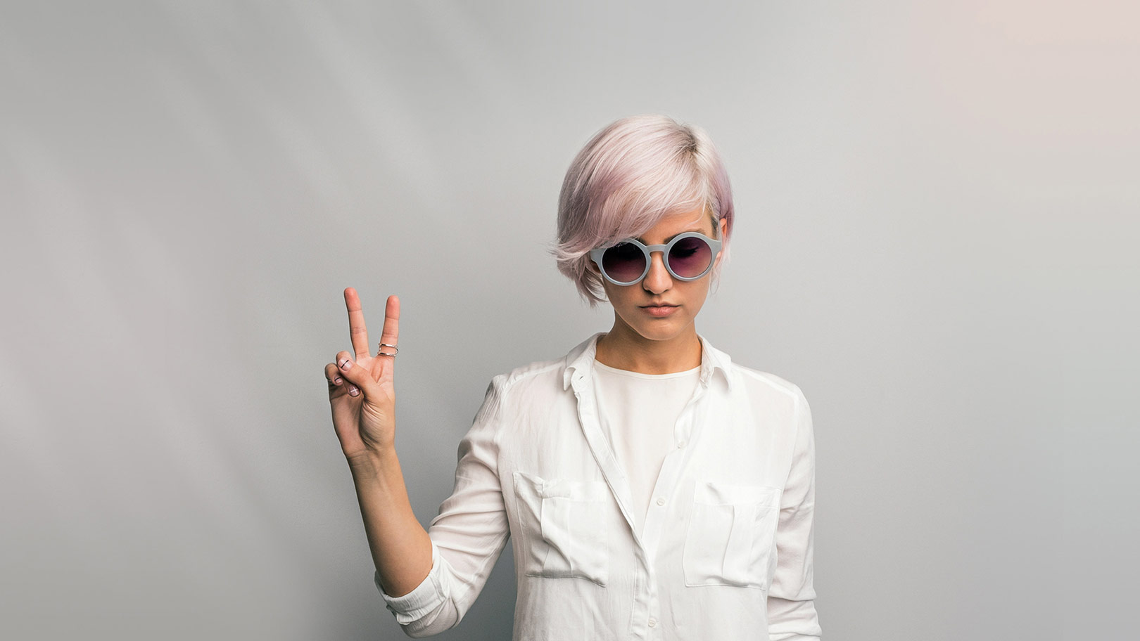 Junge Frau in weißer Bluse mit Sonnenbrille Peace