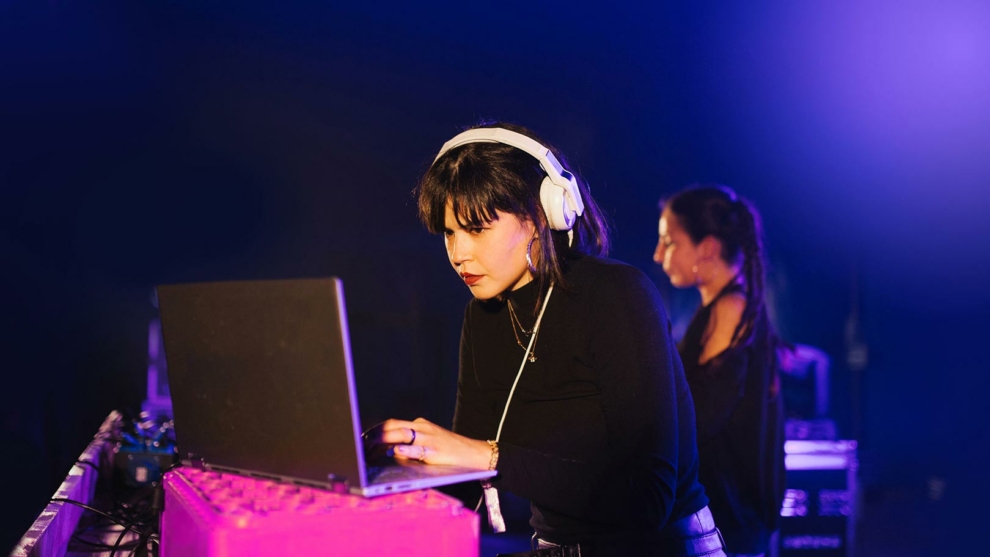 Junge dunkelhaarige Fraumit Kopfhörer konzentriert am PC
